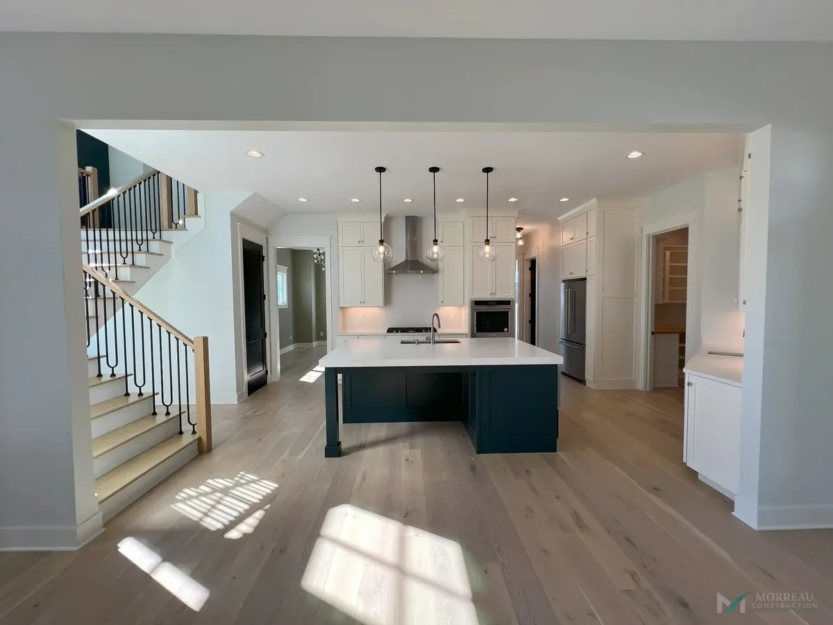 Kitchen with teal island and open staircase